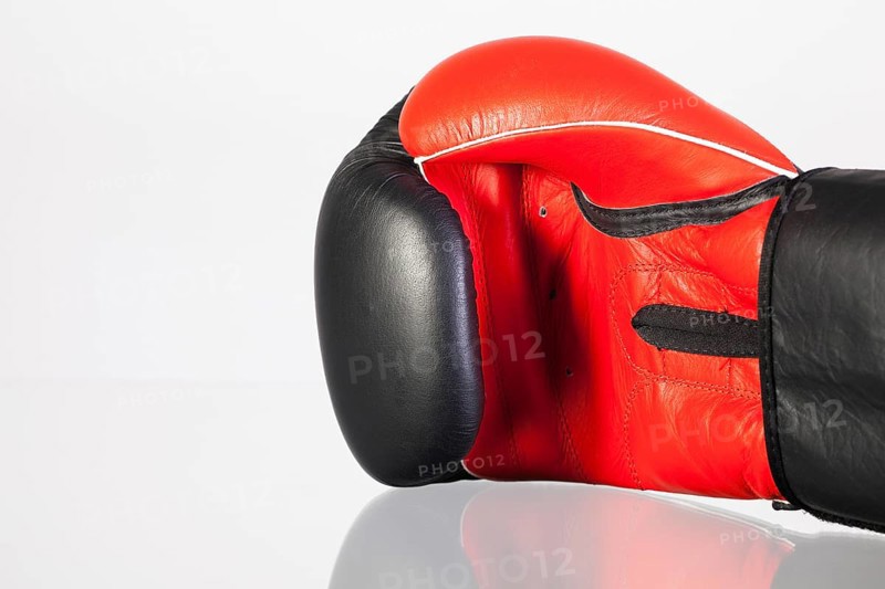 Red and black boxing gloves on a glass table isolated on white background