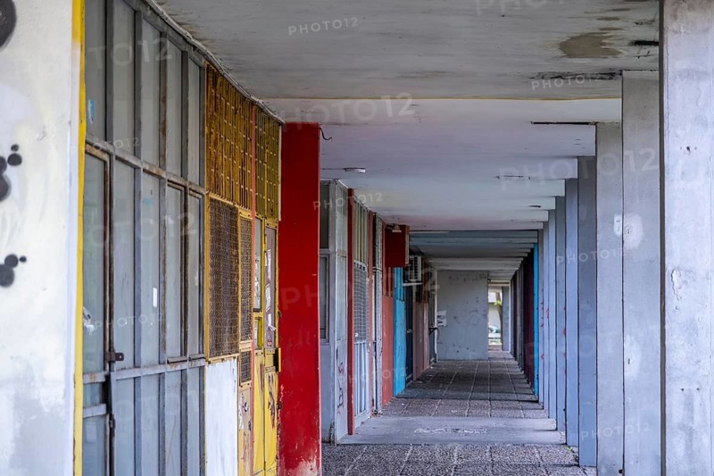 Abandoned row of shops with colourful doors and graffiti