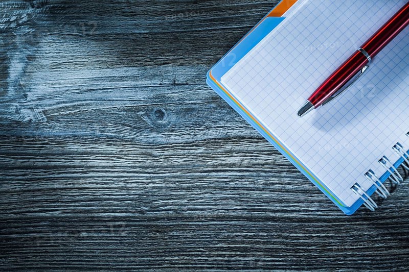 Spiral notebook pen on wooden board