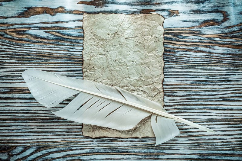Vintage paper quill on wooden board top view
