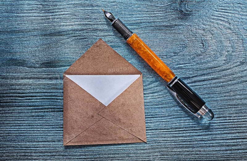 Vintage opened envelope with message fountain pen on wooden board