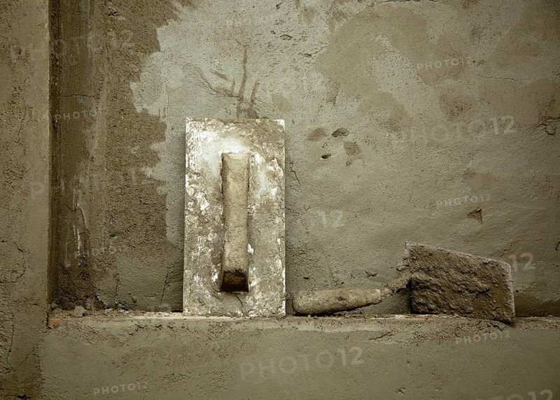 Dirty grunge cement trowel hand tools on fresh mortar wall