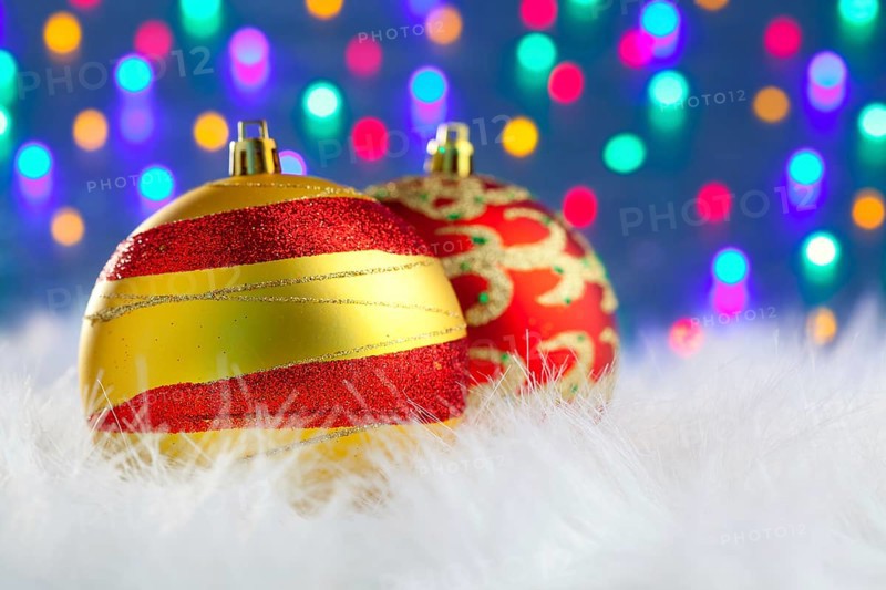 Christmas baubles on white fur and colorful lights