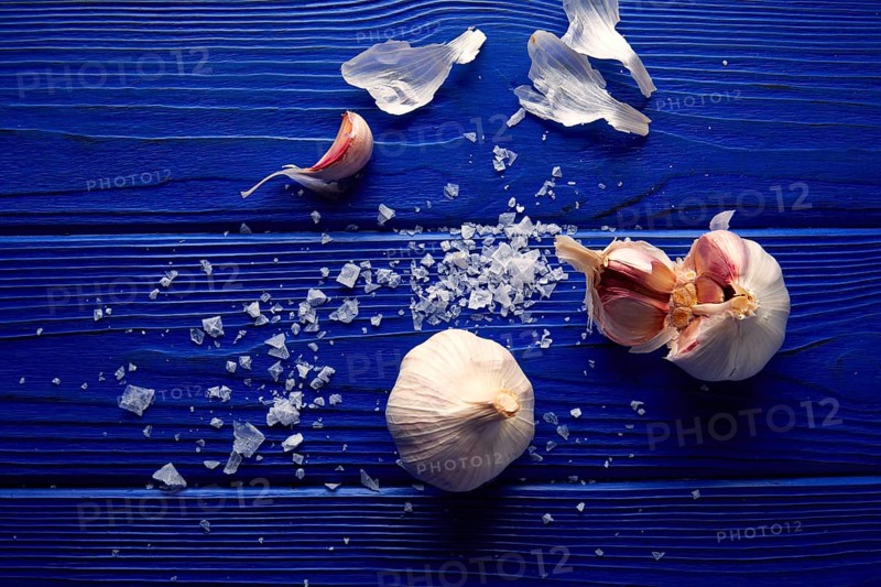 Garlic and salt spread on a blue wooden table with casual composition