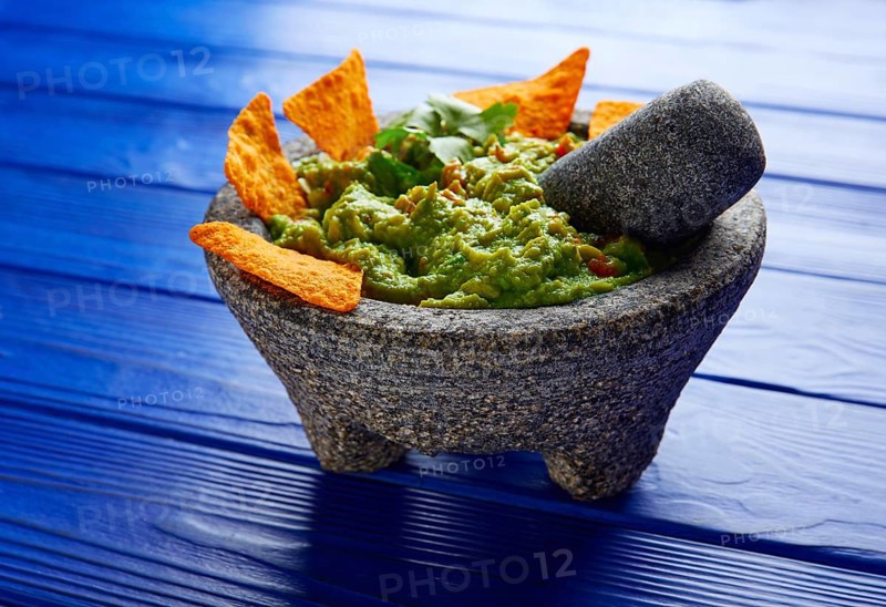 Guacamole with nachos avocado in Mexican molcajete on blue wood table