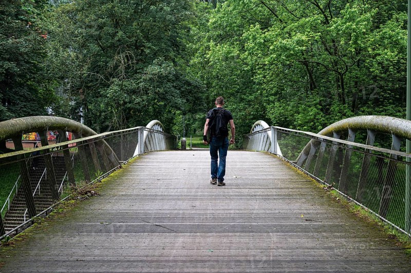 Man walking over a pedestrian bridge at Peterbos, Anderlecht, Brussels Capital Region, Belgium. Model released, staged situation