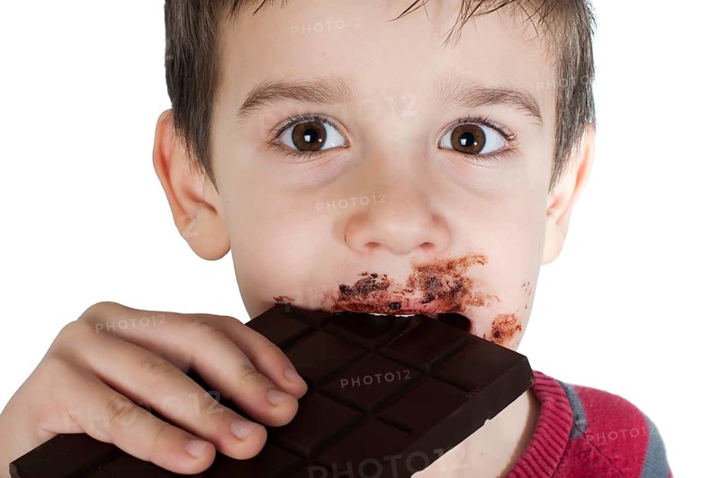 Smiling kid eating chocolate. Smeared stained with chocolate lips. White isolated