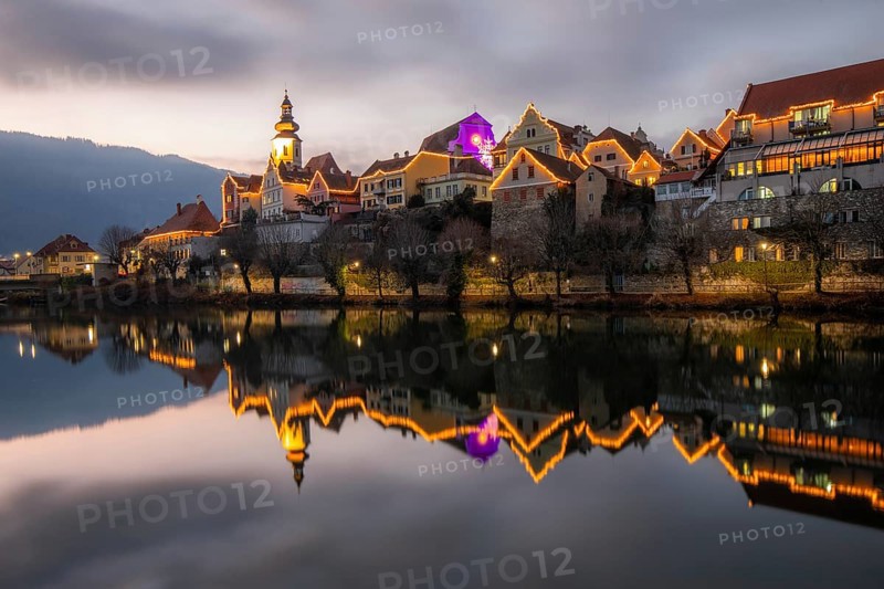 Christmas illuminated house facade of Frohnleiten reflected in the river Mur, Frohnleiten, Styria, Austria, Europe