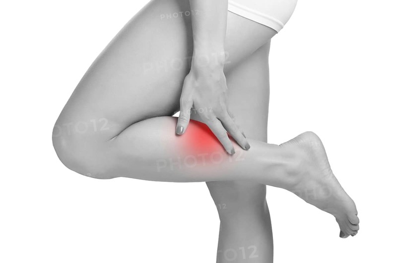 Female with pain in her lower leg, isolated in white