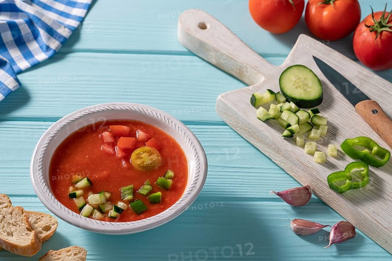 Gazpacho Andaluz is an Andalusian tomato cold soup from Spain with cucumber, garlic, pepper on light blue background