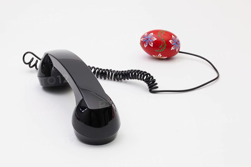 Old phone reciever and cord connection with Easter eggs. Easter hotline concept