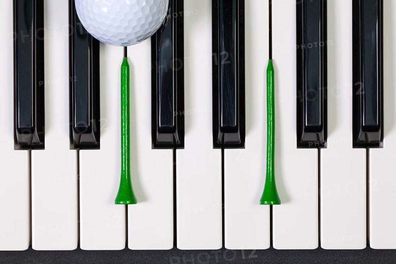 Virtuosic game - Piano keyboard and different golf balls and wooden tees