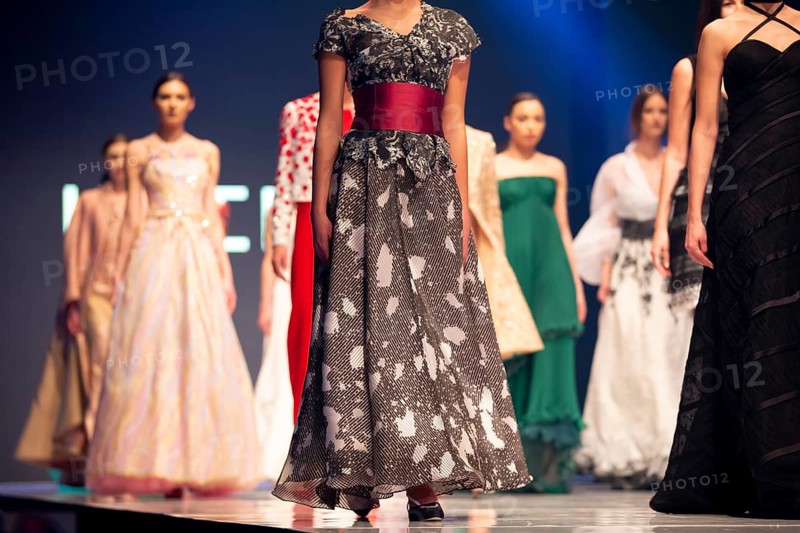 Female models walk the runway in beautiful colorful dresses during a Fashion Show. Fashion catwalk event showing new collection of clothes. Unrecognizable people