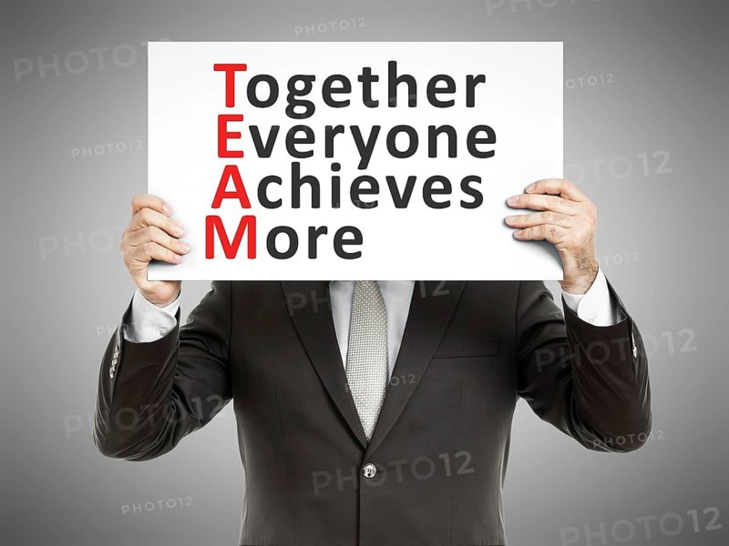 A business man holding a paper in front of his face with the text Together Everyone Achieves More