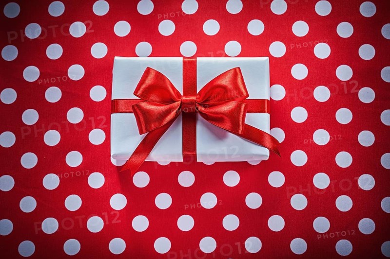 White gift box with knot on polka-dot red fabric holidays concept