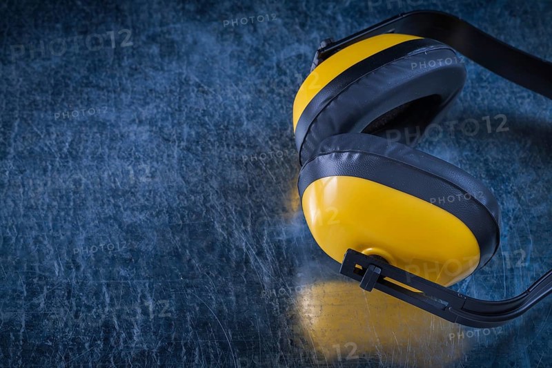 Noise reduction protective earmuffs on scratched metallic surface construction concept