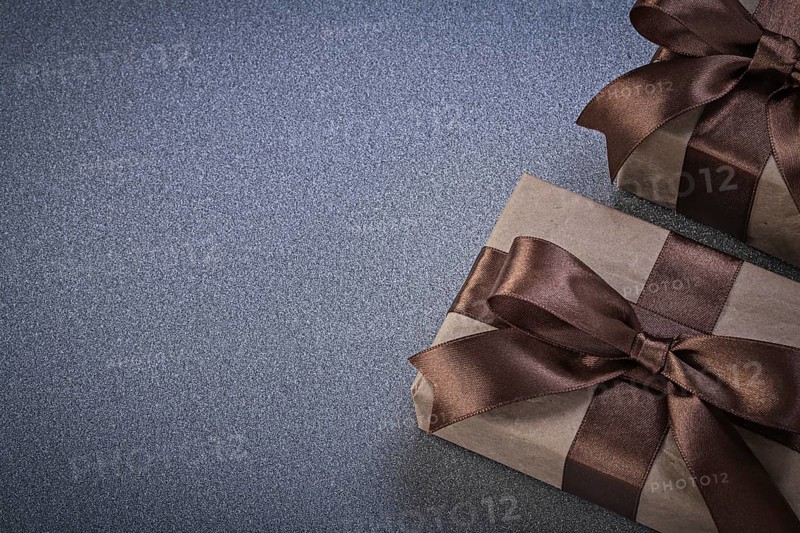 Giftboxes in brown wrapping paper on grey background celebrations concept