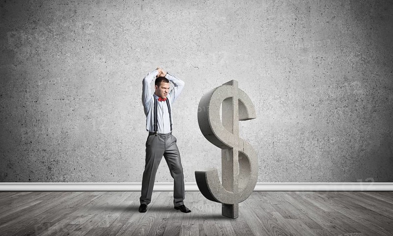 Young furious businessman going to crash with hands stone dollar symbol