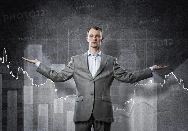 Businessman with spread arms and growing graphs on chalkboard