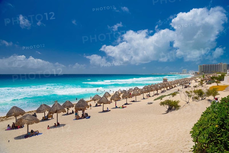 Umbrellas on a sandy beach with azure blue water on a sunny day near Cancun, Mexico, Central America