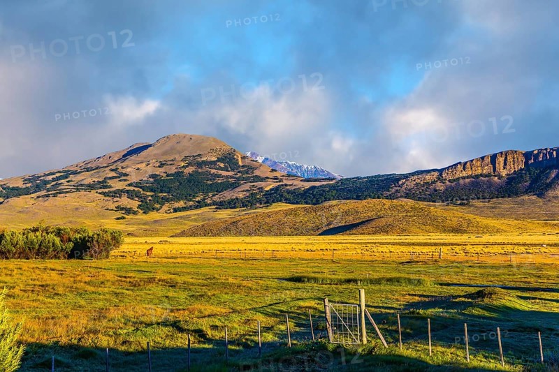 The huge possessions of a private hacienda are surrounded by distant mountains. The grass field is covered with streams. Argentine Patagonia. The concept of exotic and active tourism