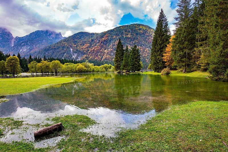 Midday in a mountain valley. Picturesque shallow lake Fuzine of glacial origin. The lake shores are flooded. Wonderful warm autumn day