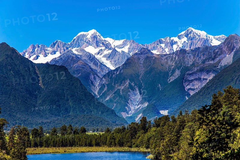 Mountain peaks covered with snow. Mirror glacial Lake Matheson surrounded by mountains Mount Cook and Mount Tasman. The concept of ecological, active and photo tourism