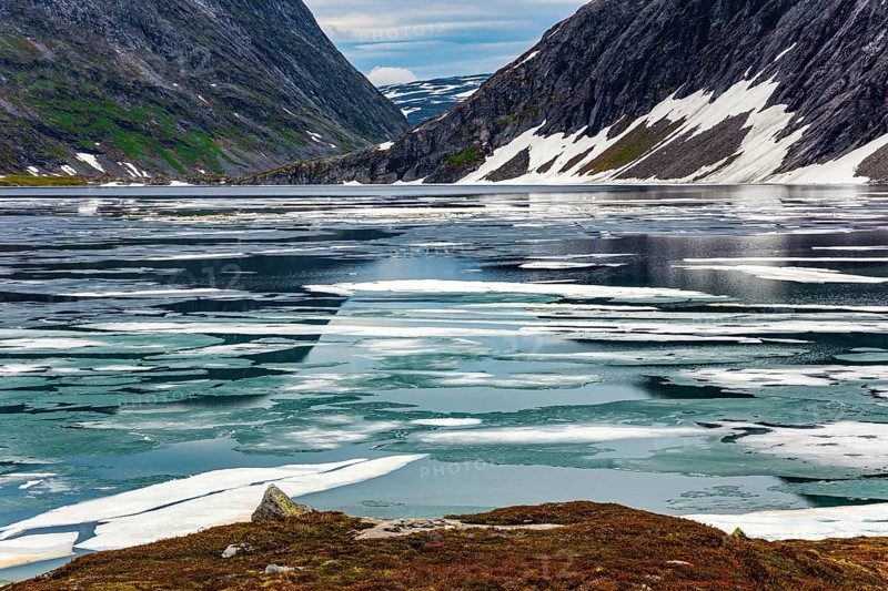 Kingdom of the Snow Queen. Lake Djupvatnet is covered with ice in July. The mountains are covered with freshly fallen snow. Summer trip to Norway