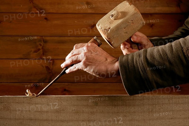 Gouge wood chisel carpenter tool hammer in hand working wooden background
