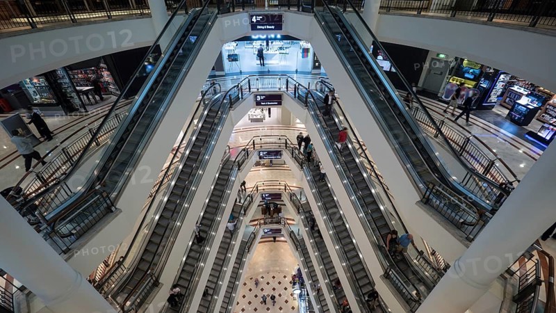 High angle shot of modern multistorey shopping mall. People traffic on the escalators of each floor. Trade centre in Petronas Twin Towers in Kuala Lumpur, Malaysia, Asia