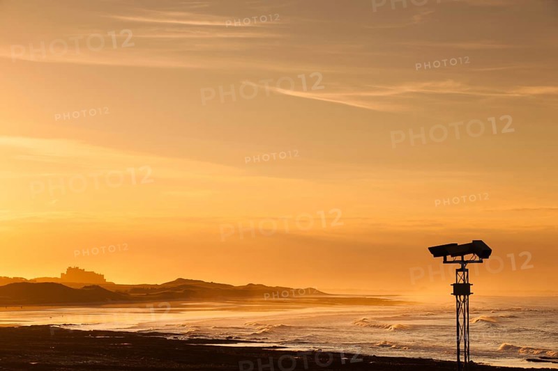 View of the Bamburgh castle in a spectacular sunset from the Seahouses, Great Britain