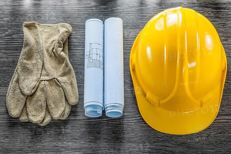 Safety gloves blueprints hard hat on wooden board