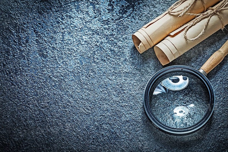 Vintage paper rolls magnifying glass on black surface