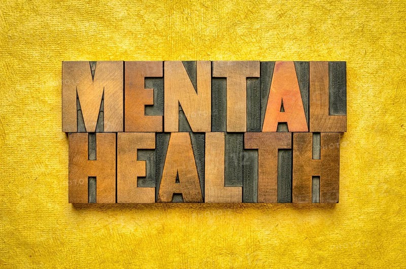 Mental health word abstract in vintage letterpress wood type printing blocks against yellow textured bark paper, wellbeing and healthcare concept