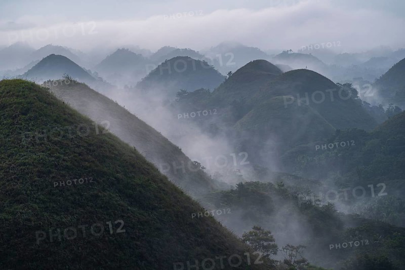 Chocolate hills on the island Bohol in the philippines at sunrise with mist and fog