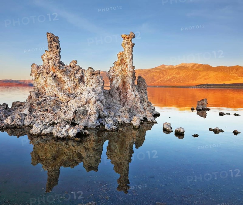 The magic of Mono Lake. Outliers - bizarre limestone formations reflected in the smooth water. Orange sunset
