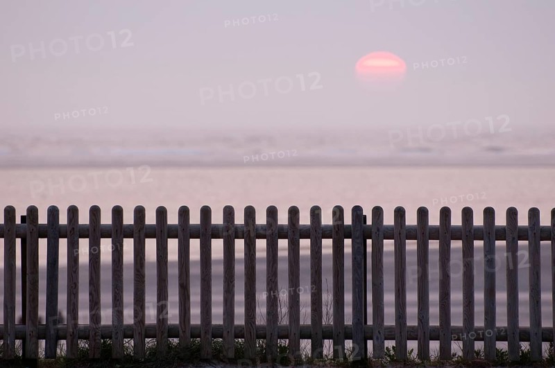 Landscape by the sea with wooden fence in the foreground and calm sunset in the background, Borkum, North Sea, East Frisia, Germany, Europe
