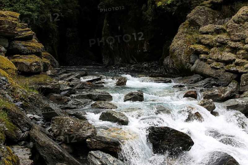 Small waterfall flows out of a dark cave