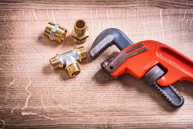 Plumbing Tools Composition Of Brass Pipe Connectors On Wooden Board and Monkey Wrench