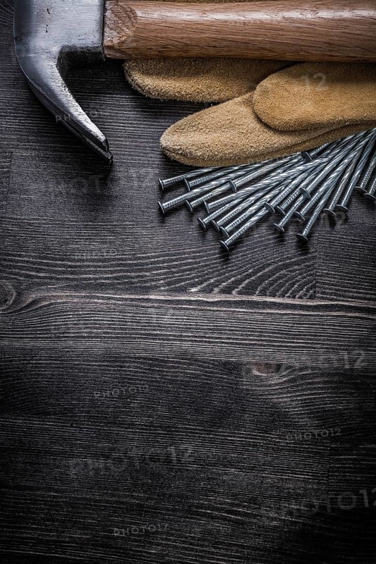 Working gloves construction nails claw hammer on vintage wooden board
