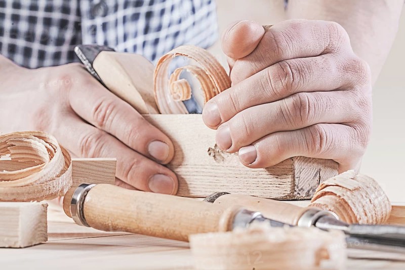 Woodworkers plane in hands of carpenter very close up