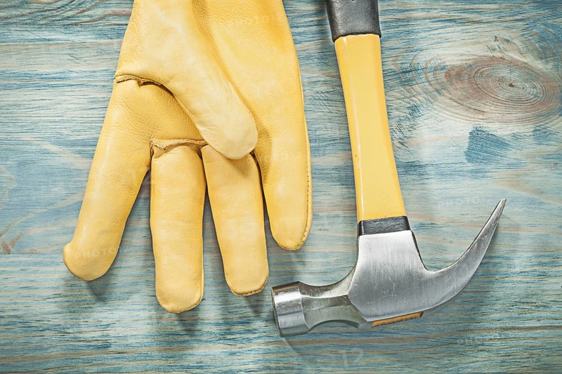 Top view of claw hammer leather protective glove on wooden board construction concept