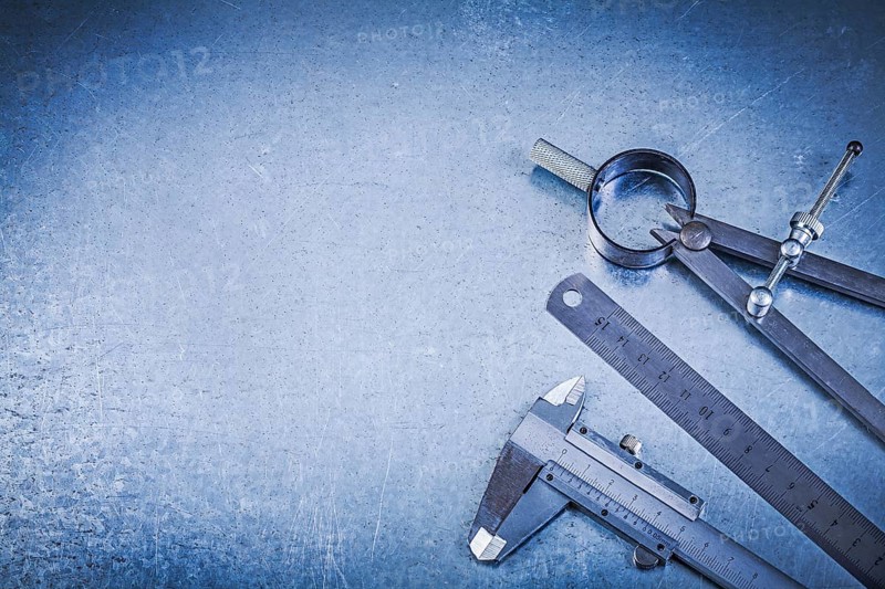 Metal construction drawing compass ruler caliper on metallic background