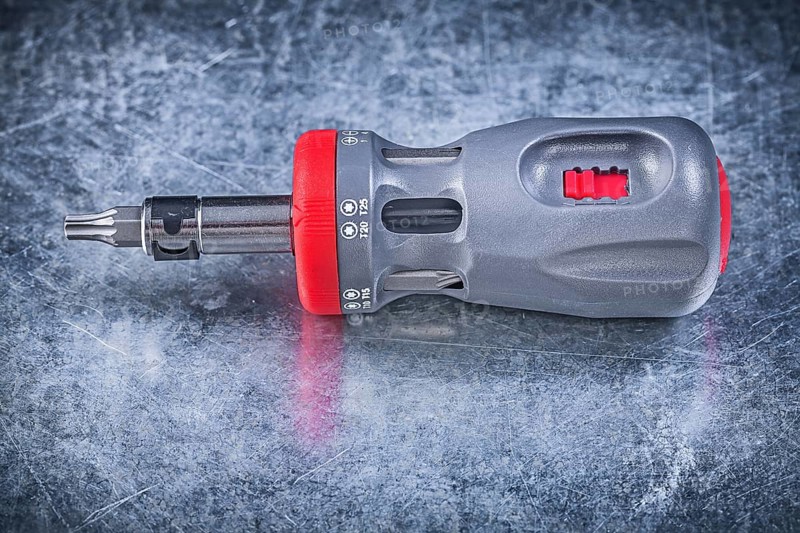 Screwdriver with replaceable bits on metallic background construction concept
