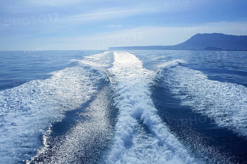 Fishing speedy boat prop wash, white wake on the blue ocean sea