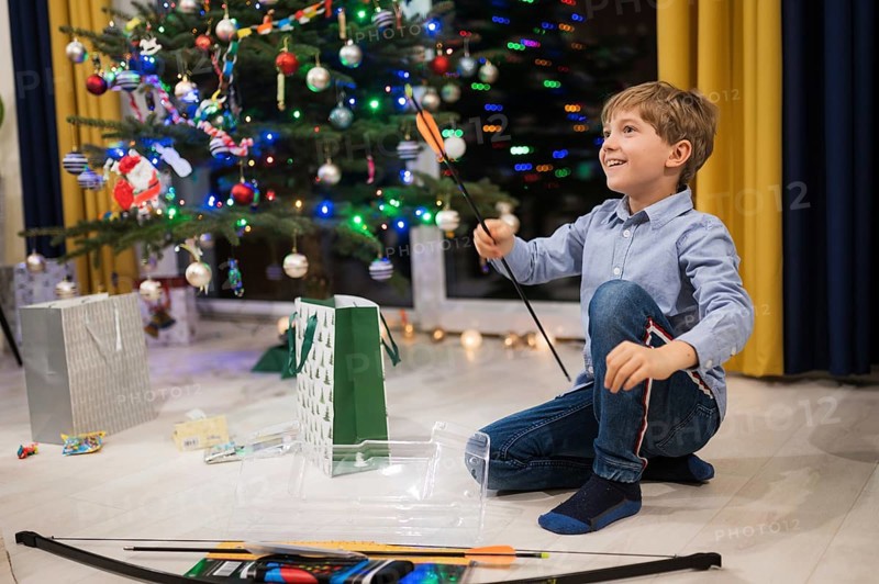 Happy boy opening a Christmas gift and Christmas tree in the background