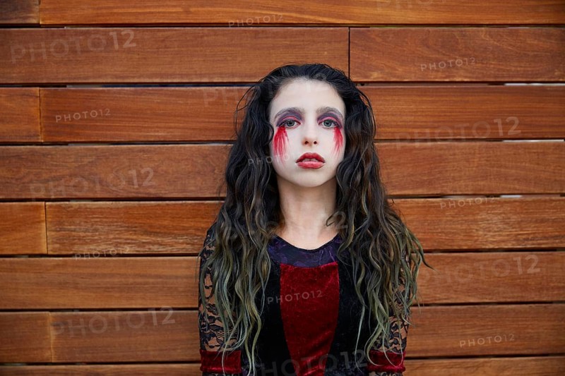 Halloween kid girl custome with bloody makeup on wooden wall