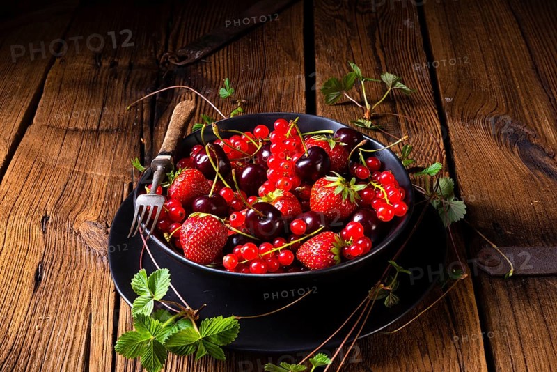 Bowl with different fruits such as strawberry, red currant, and cherry