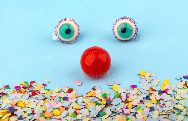 Red Nose with confetti over light blue background. Conceptual Photo to use for all funny celebration themes