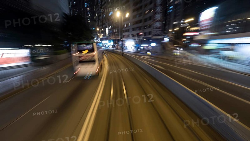 Traveling through the night city by double-decker tram. View to the rails and transport on the road. Shot in motion, Hong Kong, Asia